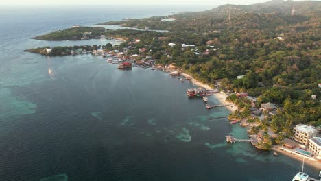Aerial-view-of-the-coast,-boats,-green-palms,-resorts,-on-the-sandy-beach-at-sunset