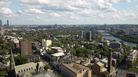 Aerial-Pan-Left-Above-Cambridge,-Massachusetts-with-Boston-Skyline-in-Background-on-Beautiful-Summer-Afternoon
