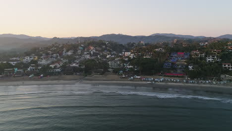 Aerial-along-coast-of-Sayulita-Mexico-beach-surf-town-at-sunrise,-4K