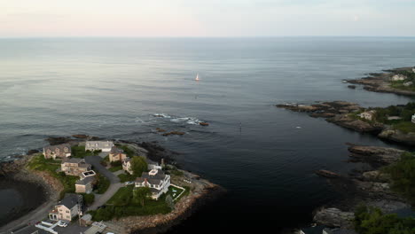 Aerial-footage-of-a-sailboat-on-the-horizon-in-Ogunquit,-Maine-at-Sunset