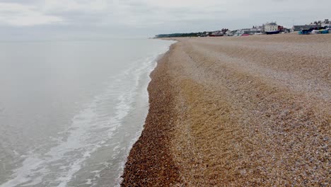 Drone-video-flying-over-small-waves-on-the-pebbled-beach-in-Deal,-Kent,-UK