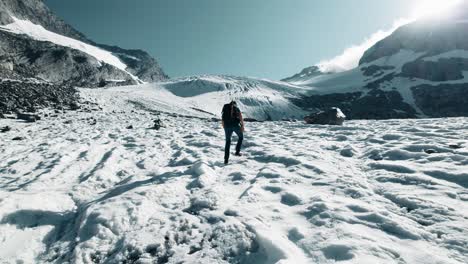 A-male-mountaineer-is-walking-with-crampons-on-a-glacier-and-some-crevasses-in-the-background