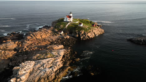 Scenic-Pan-Back-Aerial-Footage-of-Nubble-Lighthouse-in-Cape-Neddick,-Maine-at-Sunset