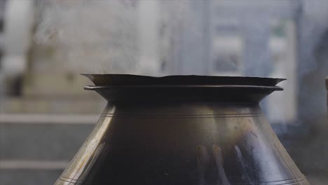 Close-up-static-shot-of-smoke-coming-out-of-typical-Indian-metal-pot