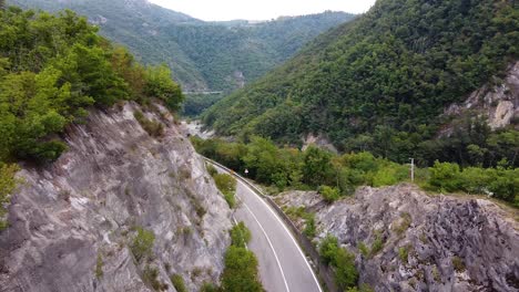 Drone-Cinematográfico-Filmado-Sobre-La-Carretera-Y-El-Río-Y-La-Naturaleza-En-Las-Montañas-Italianas