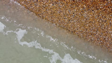 Entspannende-Aufnahmen-Von-Wellen,-Die-Langsam-über-Kies-An-Einem-Strand-Schwappen