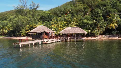 Floating-restaurant-with-a-thatched-roof-stands-on-wooden-poles-above-the-water