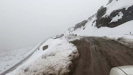 car-driving-in-himalayan-snow-cap-mountains-at-morning-in-slushy-tarmac-road