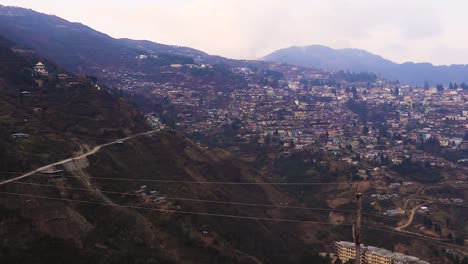 Vista-De-Urbanización-De-La-Ciudad-Desde-La-Cima-De-Una-Colina-Con-Una-Enorme-Construcción-En-El-Día-Desde-Un-Video-De-ángulo-Plano-Tomado-En-Bomdila-Arunachal-Pradesh-India
