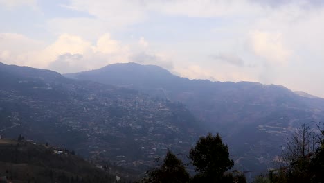 Vista-De-Urbanización-De-La-Ciudad-Desde-La-Cima-De-Una-Colina-Con-Una-Gran-Construcción-Y-Un-Lapso-De-Tiempo-En-La-Nube-En-El-Video-Del-Día-Se-Toma-En-Bomdila-Arunachal-Pradesh-India