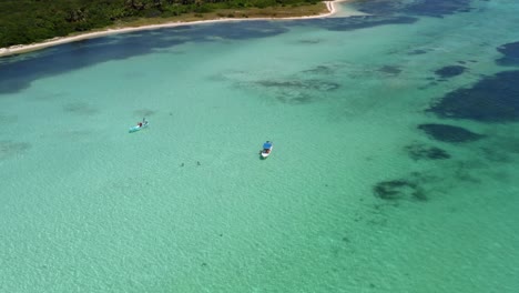 Stunning-aerial-bird's-eye-top-view-of-small-tour-boats-in-the-middle-of-a-sea-of-crystal-clear-turquoise-water-in-the-beautiful-nature-reserve-of-Sian-Ka'an-near-Tulum,-Mexico
