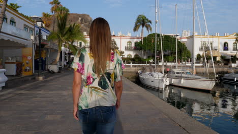 Gimbal-shot-following-young-woman-walking-on-marina-in-Canary-Islands
