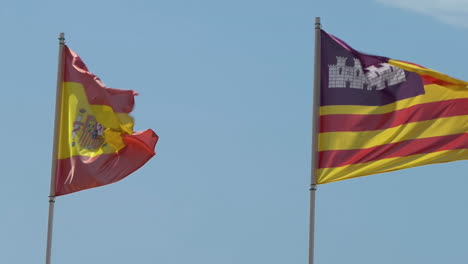 Spain-and-Balearic-Islands-an-autonomous-community-in-Spain-flags-waving-together-in-the-wind-against-a-blue-sky