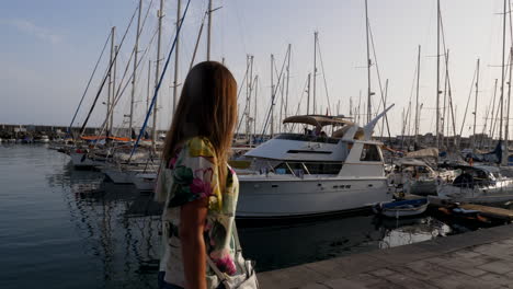 Sliding-gimbal-shot-of-young-woman-walking-on-marina-in-Canary-Islands