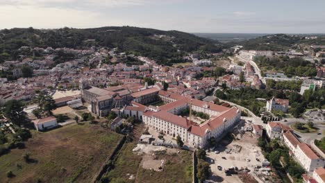 Portugal-historical-cityscape-and-catholic-monastic-complex-Alcobaça-monastery,-aerial-pan-shot