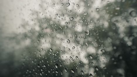 Rain-water-droplets-on-glass,-Large-rain-drops-strike-a-window-pane-during-a-summer-shower-inCosta-Rica-Jungle