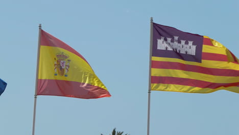 Real-fabric-flag-of-Spain-and-Balearic-Islands-an-autonomous-community-in-Spain,-waving-in-the-wind-against-a-blue-sky