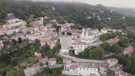 Aerial-circular-pan-shot-around-the-residence-town-palace-of-Sintra-on-a-foggy-mountain-hill