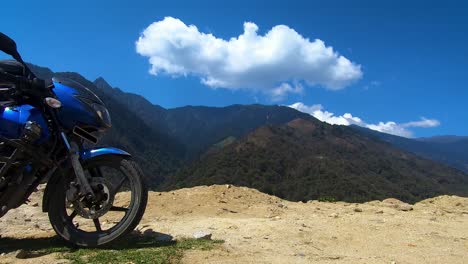 Motocicleta-En-La-Montaña-Del-Himalaya-Con-Lapso-De-Tiempo-En-La-Nube-Y-Cielo-Azul-Por-La-Mañana-Desde-Un-ángulo-Plano