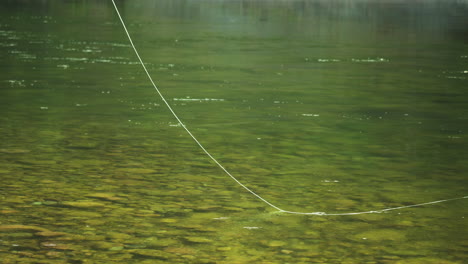 Fishing-Line-Casted-Multiple-Times-Into-Stream-with-Clear-Green-Water,-Nobody