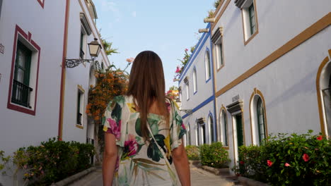 Gimbal-shot-following-young-woman-walking-on-picturesque-white-village
