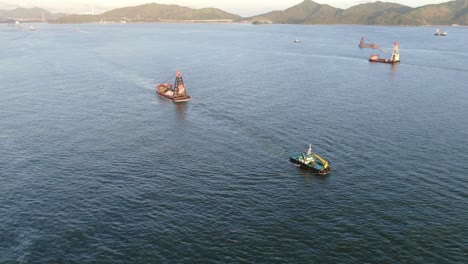 Remolcador-Tirando-De-Una-Pequeña-Barcaza-En-La-Bahía-De-Hong-Kong,-Vista-Aérea