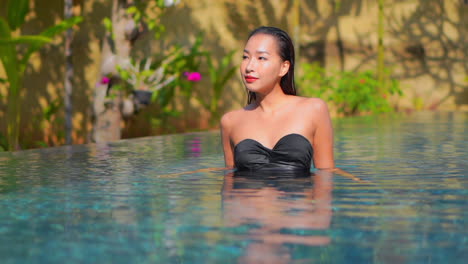 Frau,-Die-Im-Schwimmbad-Spazieren-Geht-Und-Ihr-Nasses-Haar-Mit-Beiden-Händen-Bei-Sonnenuntergang-Glättet,-Bali-In-Zeitlupe
