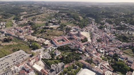Drone-capturing-Alcobaça-cityscape-with-the-monastery-at-center,-aerial-circular-pan-shot