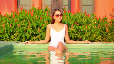 Front-view-of-an-Asian-lady-in-a-swimming-pool-wearing-white-swimwear-and-sunglasses