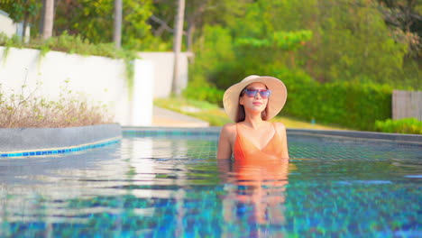 Stylish-fashionable-woman-sitting-inside-swimming-pool-water-at-Exotic-hotel-in-Turkey-handheld-slow-motion