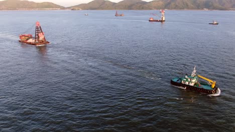 Tugboat-pulling-a-small-Barge-in-Hong-Kong-bay,-Aerial-view