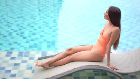 Eine-Junge-Hübsche-Frau-Entspannt-Sich-Auf-Einer-Rattanliege-Neben-Einem-Resort-Swimmingpool