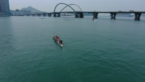 Dragon-Boat-team-rowing-to-the-pace-of-an-onboard-Drummer,-Aerial-view