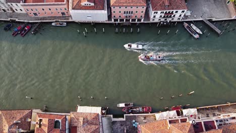 Aerial-top-down-view-of-boats-traveling-through-the-residential-canals-of-Venice,-Italy