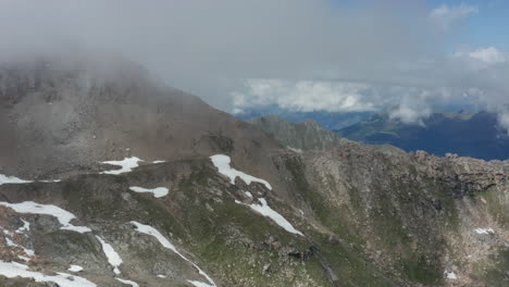 Aerial-of-rocky-mountain-slope-with-thick,-dark-clouds-forming