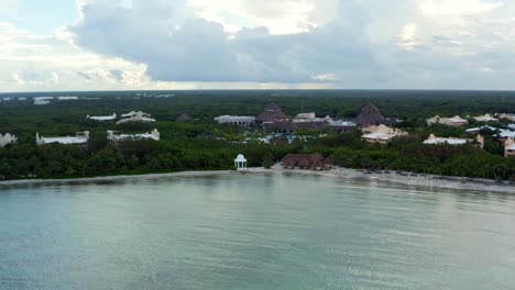 Beautiful-dolly-in-aerial-drone-shot-of-the-tropical-coastline-of-playa-del-carmen-with-large-vacation-resorts-in-Riviera-Maya,-Mexico-on-a-warm-sunny-summer-day