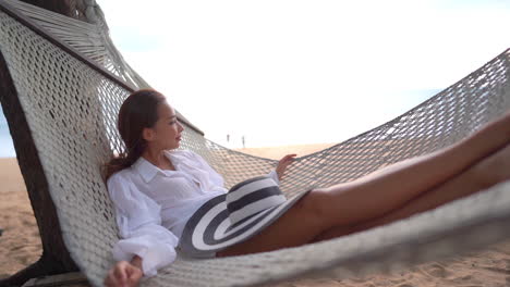 Asiatische-Frau,-Die-Sich-Entspannt,-In-Einer-Strandhängematte-Unter-Baum-Liegend