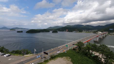 Luftaufnahme-Des-Verkehrs-An-Der-Geoje-daegyo-brücke-Mit-Booten,-Die-über-Die-Geojedo-insel-In-Südkorea-Segeln