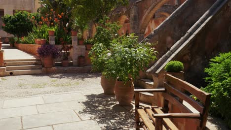 medieval-Mediterranean-old-town-with-picturesque-green-potted-plants-and-flowers-in-Greek-Orthodox-monastery-Agia-Triada-Holy-Trinity,-Crete-Greece