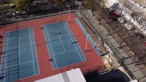 Aerial-birds-eye-shot-of-tennis-double-playing-game-on-tennis-court-during-sunlight,4K