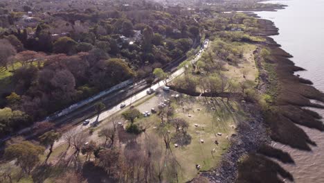Aerial-flight-over-coastal-road-with-driving-cars-next-to-Rio-de-la-Plata,Buenos-Aires