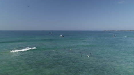 Luftumkreisende-Surfer-Im-Blauen-Wasser-Mit-Kleinen-Booten-Im-Hintergrund,-4k