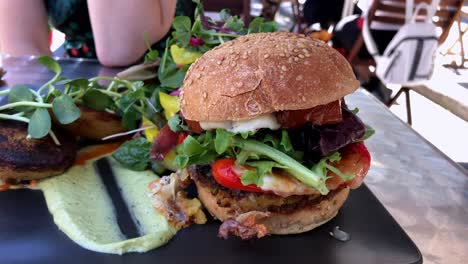 Ensalada-Grande-Y-Hamburguesa-Vegana-En-Un-Restaurante-Al-Aire-Libre