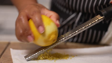 Black-woman's-hands-seen-zesting-a-lemon-on-a-grater-to-use-the-peel-shavings-as-a-tasty-ingredient