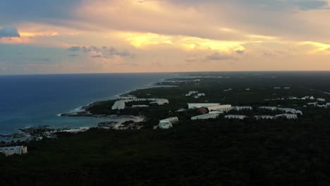 Stunning-aerial-drone-shot-of-a-tropical-Mexican-coastline-line-full-of-vacation-resorts-in-Riviera-Maya-between-Tulum-and-Cancun-during-a-warm-golden-yellow-summer-sunset