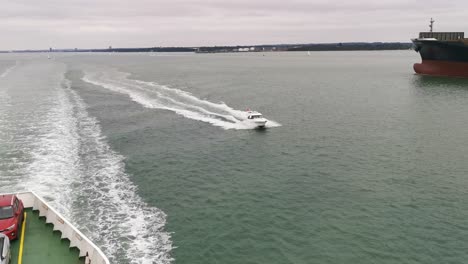 A-speedy-and-expensive-boat-trying-to-get-past-a-big-channel-ferry-going-from-southampton-to-east-cowes,-on-a-grey-and-overcast-day-in-the-middle-of-nowhere