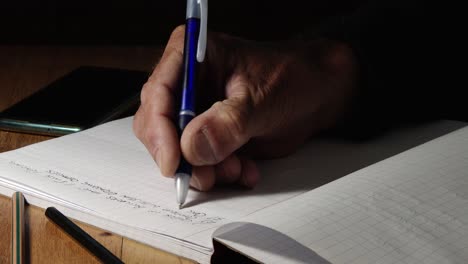 Ein-Mann,-Der-Mit-Einem-Kugelschreiber-In-Einen-Notizblock-Schreibt,-Nahaufnahme-Seiner-Hände