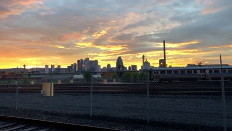 A-tranquil-golden,-red,-and-blue-sunset-over-the-skyline-of-Montreal-and-an-empty-rail-line