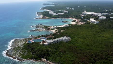 Beautiful-tilting-up-aerial-drone-view-of-the-tropical-coastline-of-playa-del-carmen-with-large-vacation-resorts-in-Riviera-Maya,-Mexico-on-a-warm-sunny-summer-day