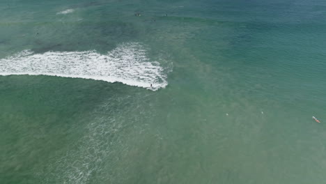 Aerial-following-surfer-as-they-gracefully-ride-wave-towards-shore,-4K
